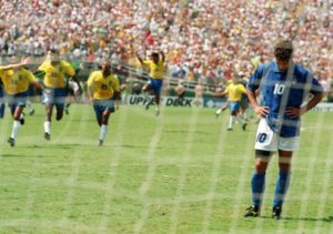 Diego Maradona, trophée en main, est porté en triomphe. Le 29 juin 1986 à Mexico, l’Argentine bat l’Allemagne 3-2  En 1986, la RFA perd encore en finale, cette fois contre l’Argentine (3-2), portée par le joueur qui a le plus nettement survolé, tout seul, une Coupe du monde, Diego Maradona.  Le « Pibe de oro » marque cinq buts, dont deux doublés contre l’Angleterre en quarts (2-1) et la Belgique en demies (2-0). Les deux buts face aux Anglais sont restés dans l’histoire: le premier, horrible, marqué de la main et non signalé par l’arbitre; le second, magnifique, quatre minutes plus tard, en dribblant toute la défense et le milieu anglais.  En 1986, c’est aussi la première qualification d’une équipe africaine pour le deuxième tour. Le Maroc domine un groupe où figurent l’Angleterre, le Portugal et la Pologne.  En finale, Maradona est surveillé de près par les Allemands mais il s’échappe une fois pour donner le but de la victoire à Jorge Burruchaga (84e), alors que la RFA venait de revenir de 0-2 à 2-2.  En 1990, le génial N.10 guide encore l’Argentine en finale, mais cette fois l’Allemagne prend sa revanche (1-0), pour sa troisième finale de rang.  Les autres héros de 1990 sont les Lions Indomptables du Cameroun, portés par un buteur de 38 ans, Roger Milla (4 buts), premiers quarts de finalistes du continent africain, battus par l’Angleterre (3-2 a.p.).